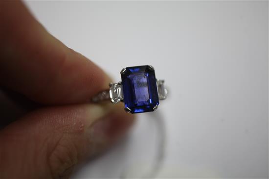 An attractive platinum, three stone sapphire and diamond ring with diamond set shoulders, size O.